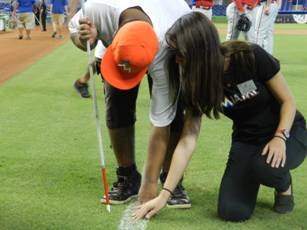 Summer camp student Frankie Young touches the grass along the first baseline with transition summer camp coordinator Emily Nostro.