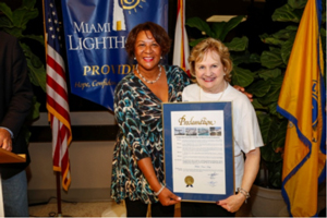 Marie Bell representing Mayor Carlos Gimenez presents Miami-Dade County Proclamation to CEO Virginia Jacko