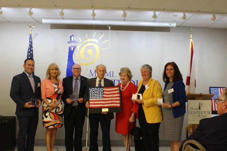 Representative Nicholas Duran, School Board Member Mari Tere Rojas, Representative David Richardson, Senior Group Activities Program Client Nick with handmade American Flag, President & CEO Virginia Jacko, Commissioner Sally Heyman and Mayor of North Miami Beach Beth Spiegel