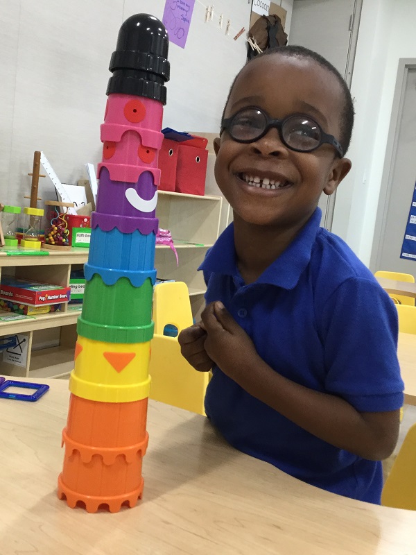 Jowayne proudly displays his tower built from colored, stackable cups